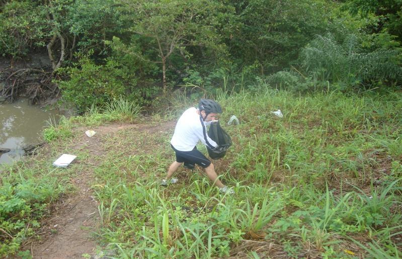 Pesquisador recolhendo resíduos às margens do Rio dos Mangues. 